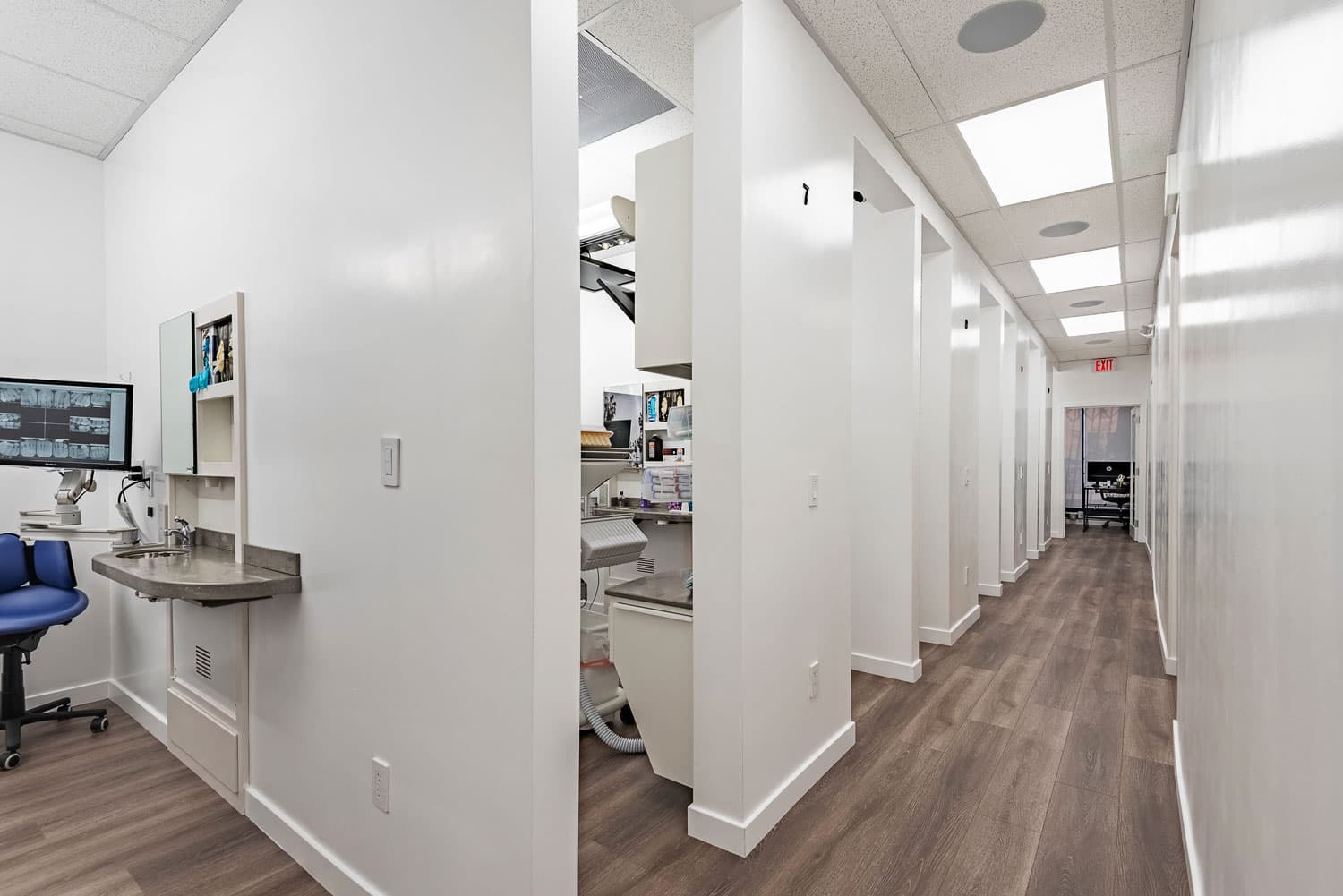 The treatment-room corridor at 360 Dental, with chairside monitors in each bay