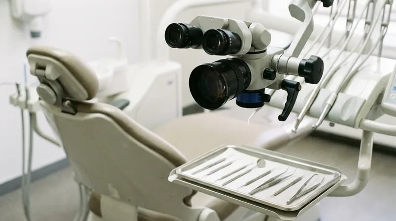 Dental operating microscope positioned over a treatment chair in a specialist operatory