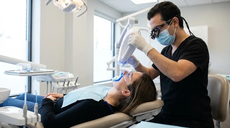 Patient receiving in-office teeth whitening treatment with a dental whitening lamp