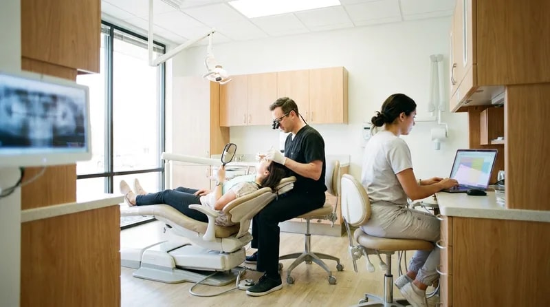 Dentist carrying out a thorough first examination while an assistant records findings nearby
