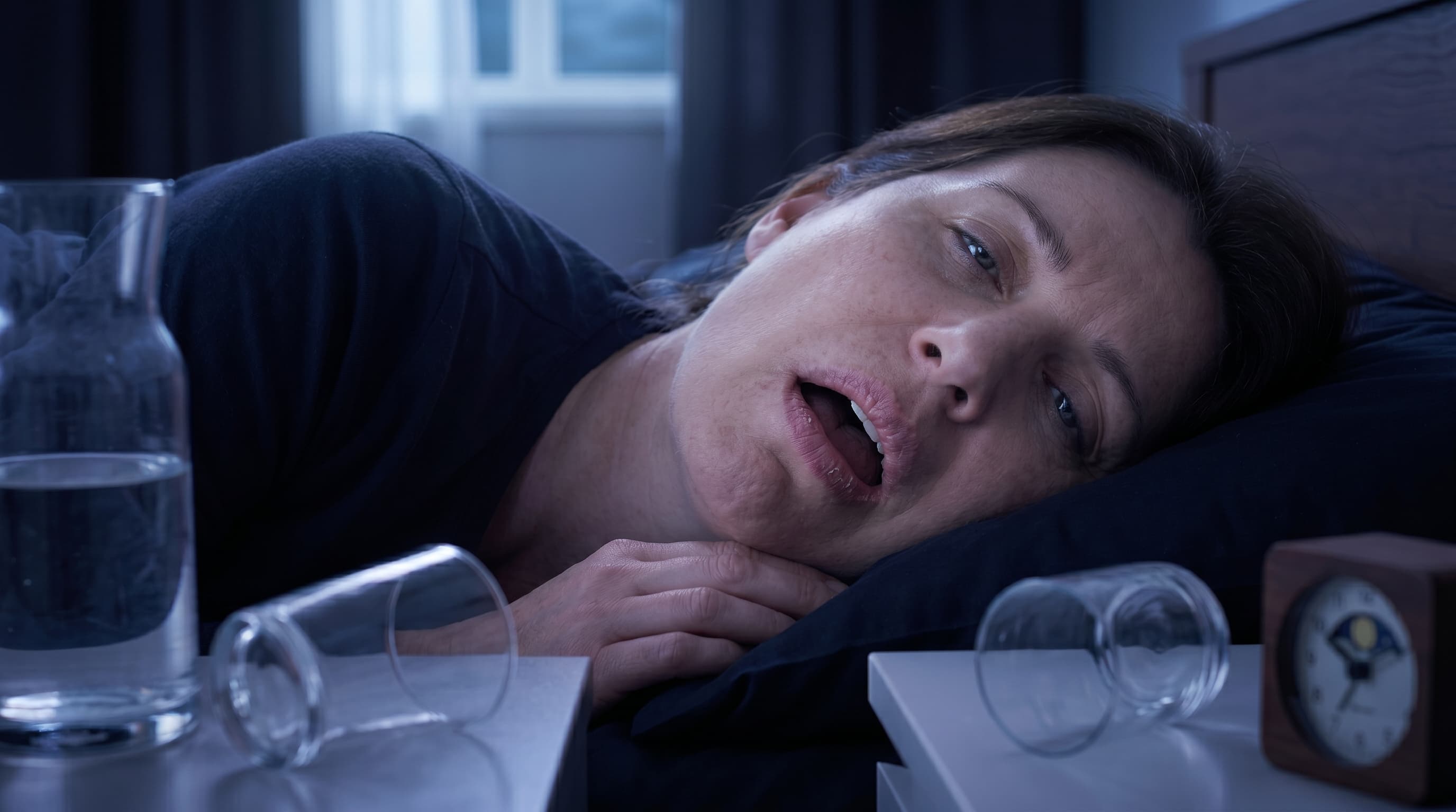 Glass of Water on Bedside Table with Soft Lamp Glow at Night
